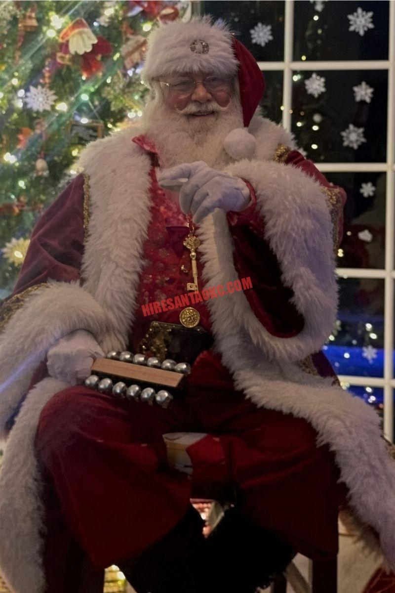 Santa home visit in Oklahoma City: Santa seated holding sleigh bells by a window.